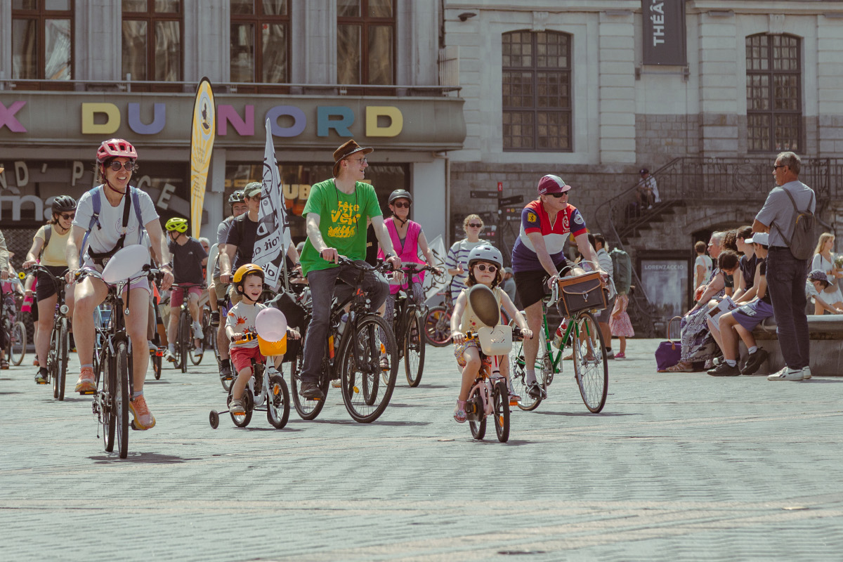 Photo d'une enfant d'environ 4 ans sur sont petit vélo. Elle est sur la grand place de Lille au milieu des autres participants